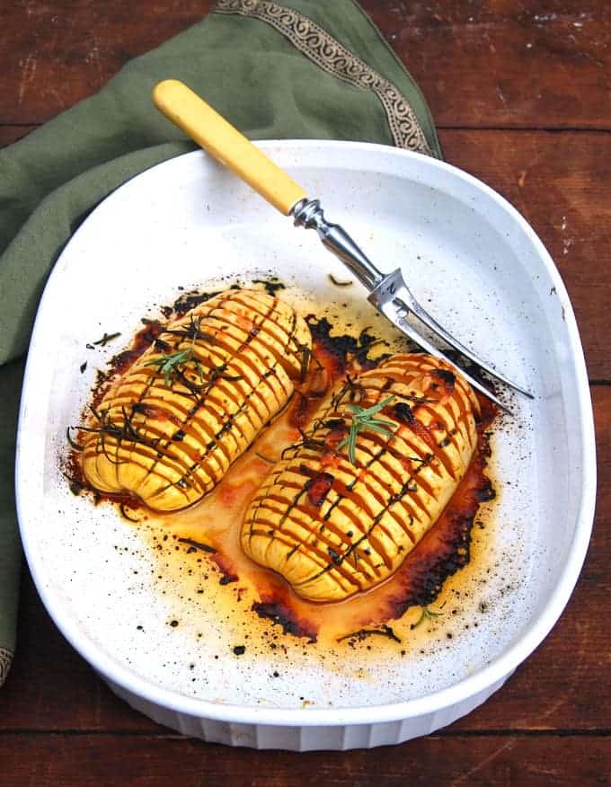 Hasselback Delicata Squash in white baking pan with fork.