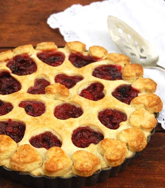 Vegan Cranberry Tart with heart-shaped cutouts in a pie dish with pie server on the side.