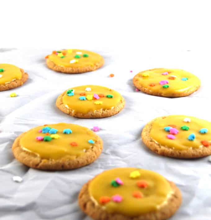 Vegan Cardamom Sugar Cookies with Mango Icing on parchment paper.