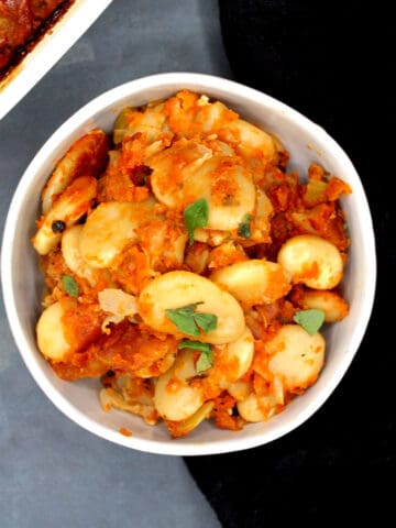 Greek gigantes in a bowl with oregano garnish.