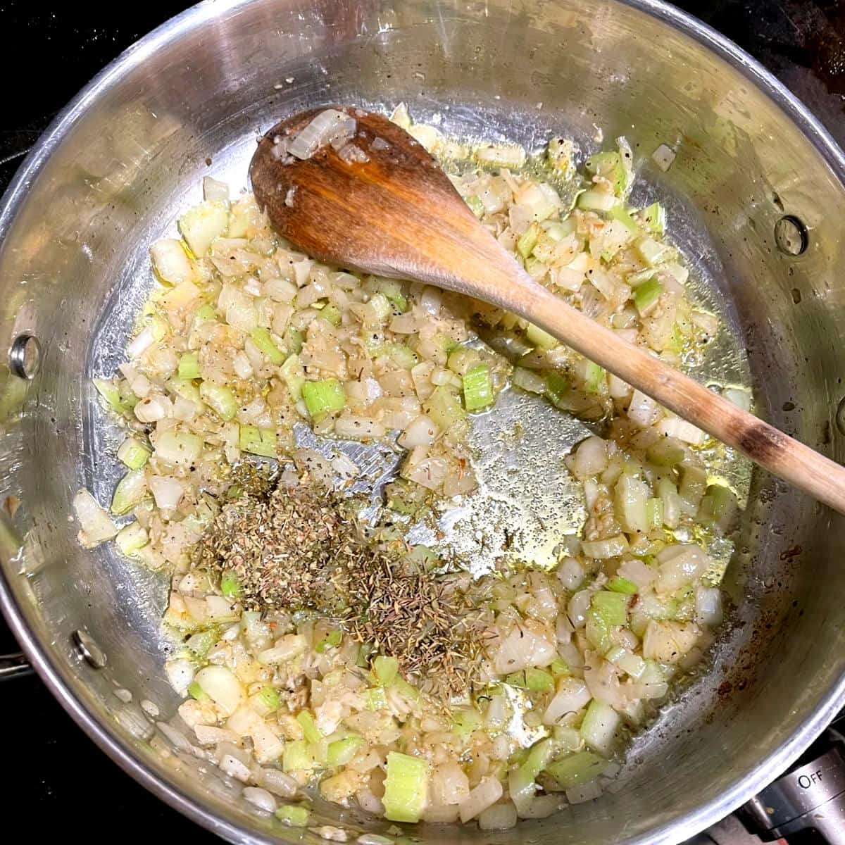 Thyme and oregano added to veggies in saucepan.