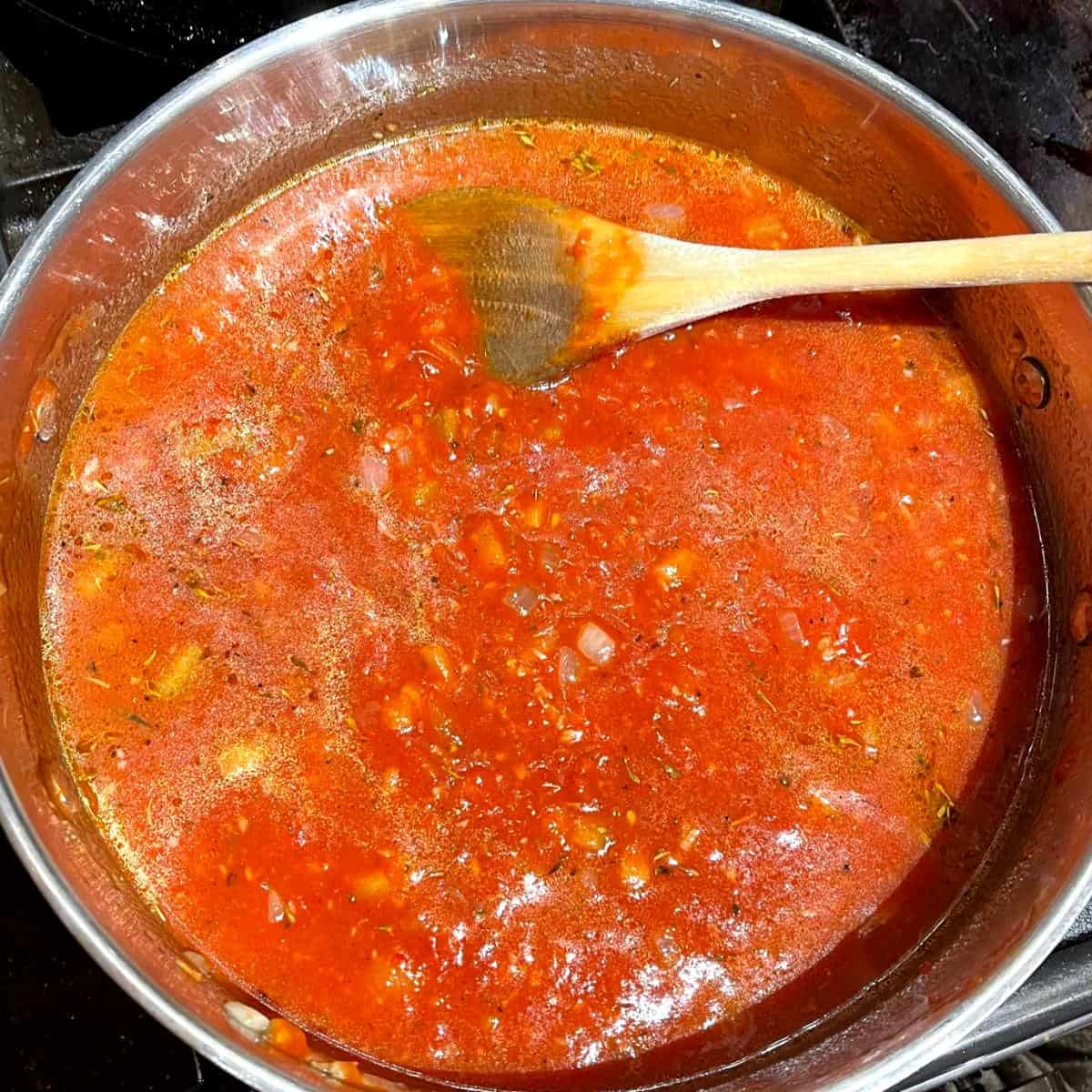 Stock added to tomatoes in saucepan.
