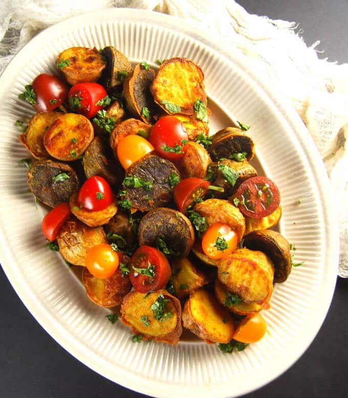 Crunchy Chickpea Roasted Potatoes in a white serving platter with cherry tomatoes.