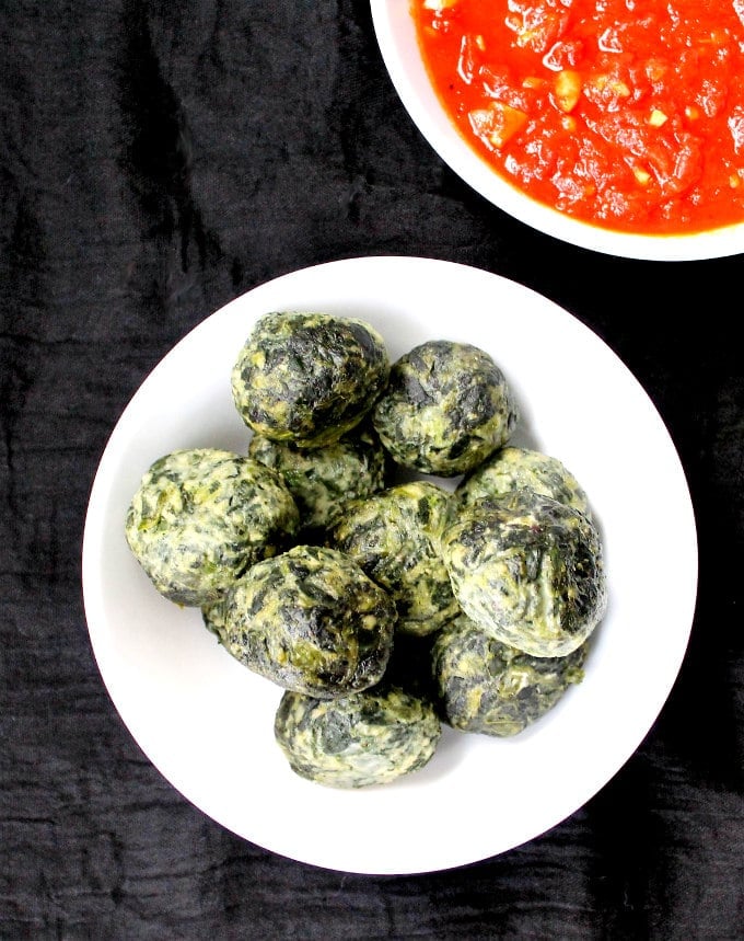 Photo of vegan Spinach Cashew Ricotta Dumplings or gnocchi verde in a white bowl.
