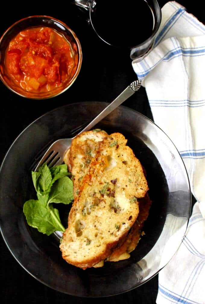 Vegan Savory Herb French Toast in a plate with a fork, tomato chutney, and coffee | HolyCowVegan.net