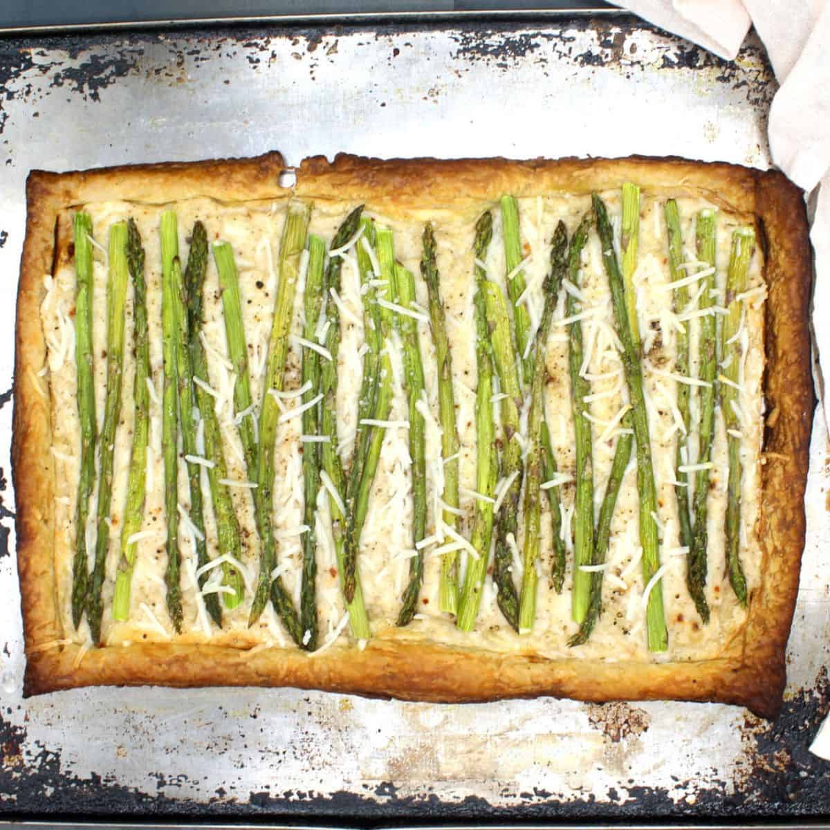 Baked vegan asparagus pizza on baking sheet.