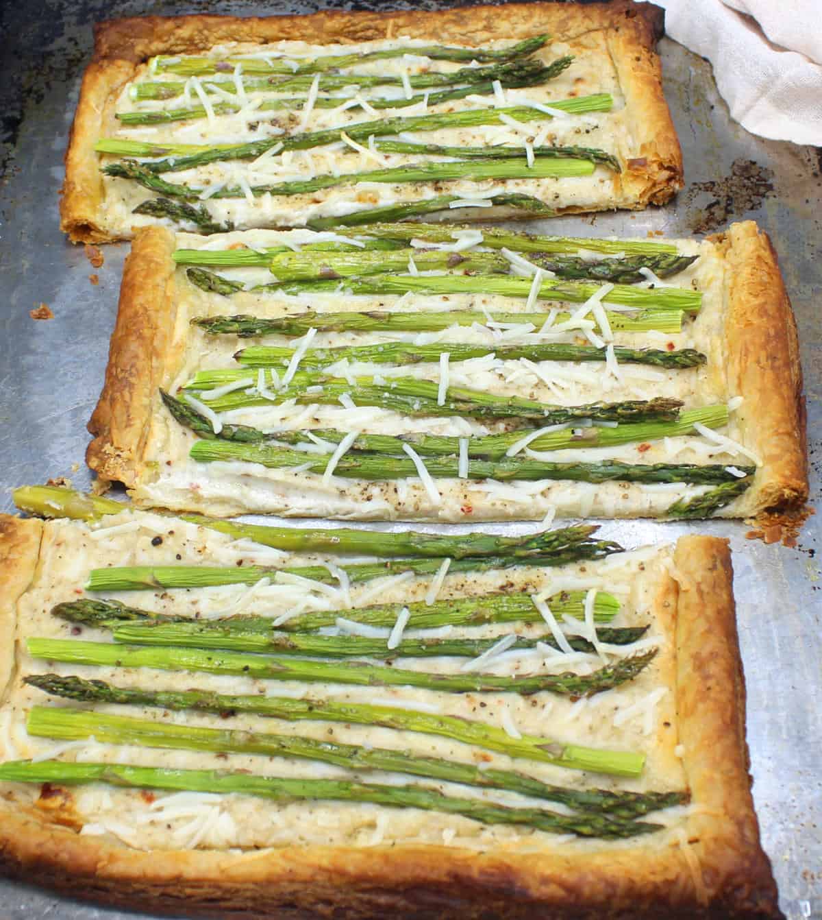 Vegan puff pastry asparagus pizza cut into three slices.