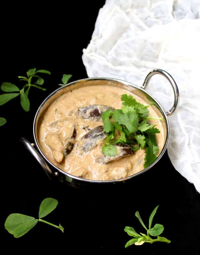 Photo of Eggplant in peanut sauce, glutenfree, vegan. in a karahi bowl with methi and cilantro.