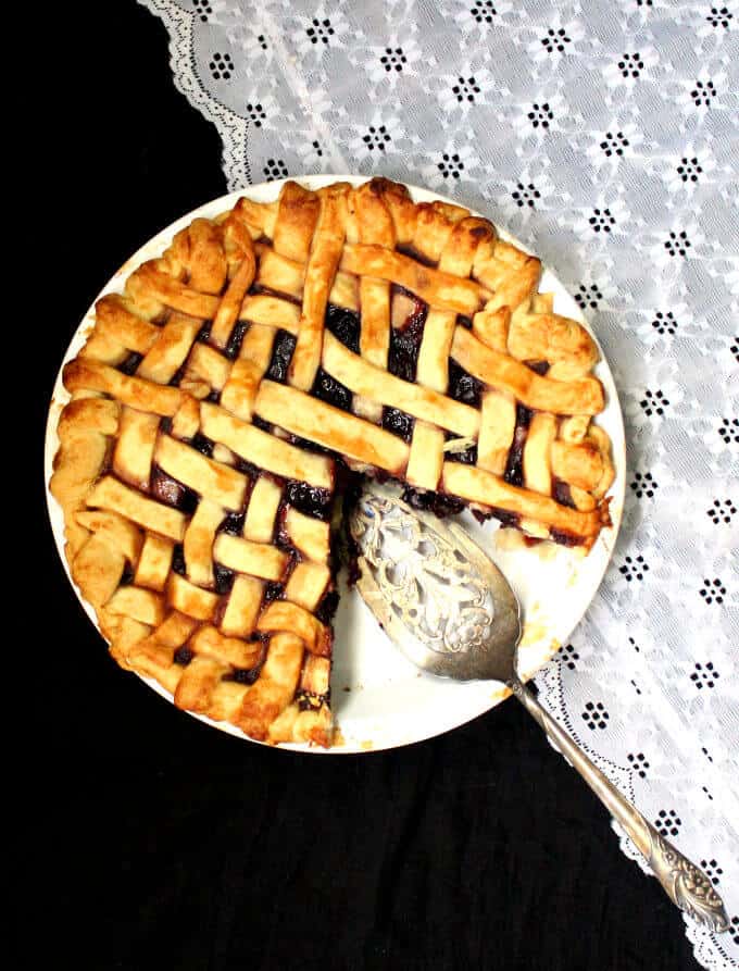 Vegan Cherry Pie in white pie plate with silver serving spoon.