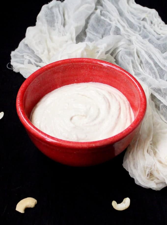 A red bowl with thick cashew yogurt.
