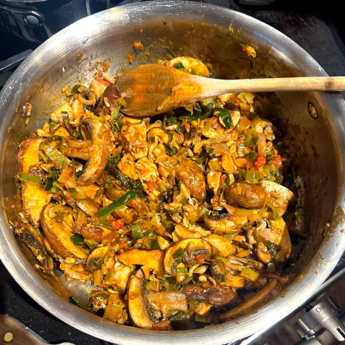 Mushrooms stirred into the leeks and tomatoes and flour in pan.