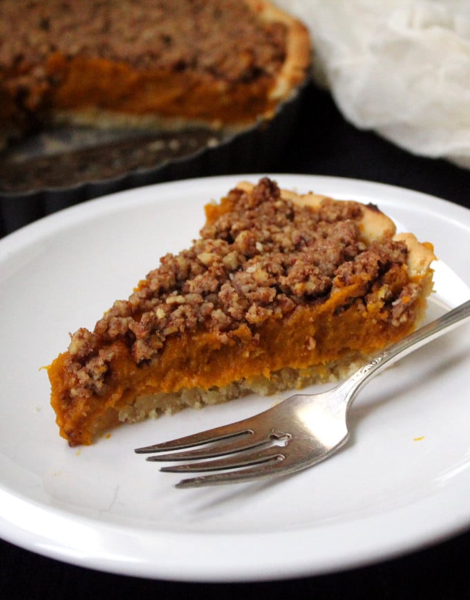 A slice of the vegan Pumpkin Praline Tart in a white plate with fork.