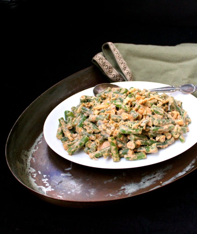 Front photo of Vegan Creamy Chipotle Green Beans in a white platter in a copper pan with green napkin.