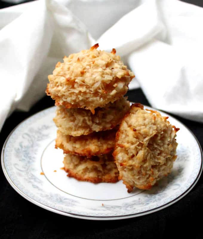 Vegan Coconut Almond Macaroons, stacked on a blue and white plate with a white napkin in background.