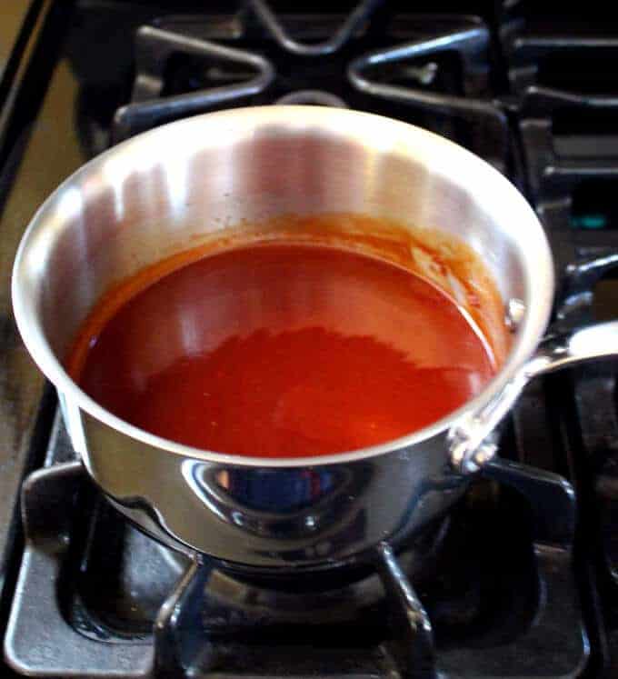 Barbeque sauce cooking on stove in saucepan.