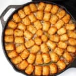 Vegan tater tot casserole in cast iron griddle with crispy tater tots.