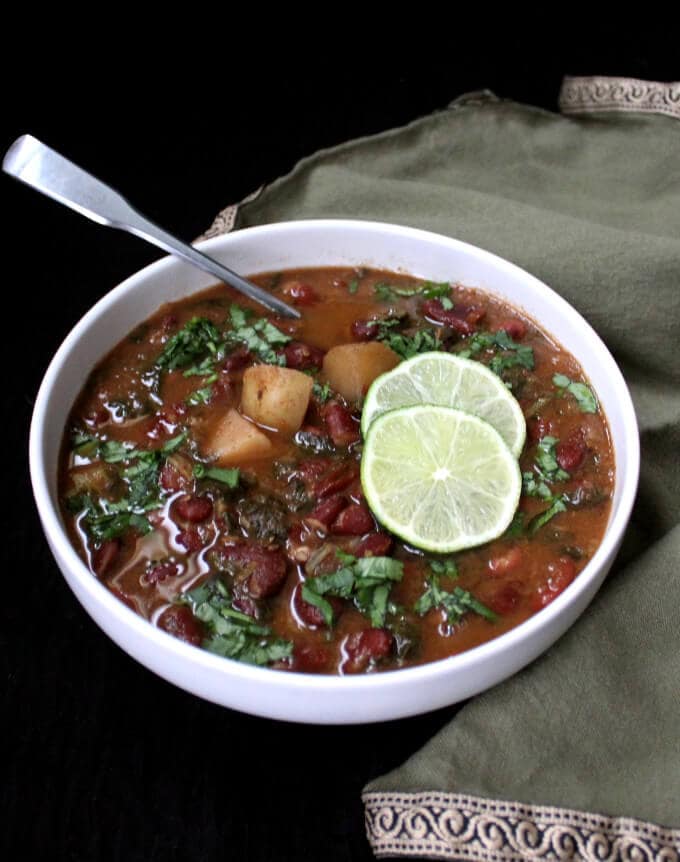 A bowl of instant pot kidney beans curry with slices of lime.