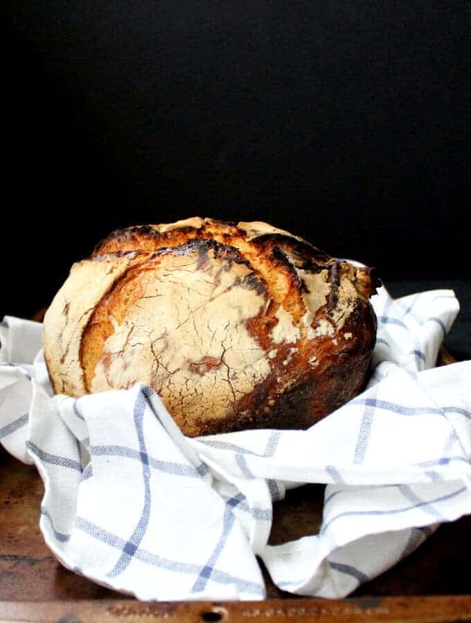 Sourdough Bread on a blue and white checked kitchen towel against a black background.