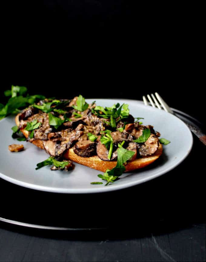 Mushrooms on Toast on plate with parsley and a fork.