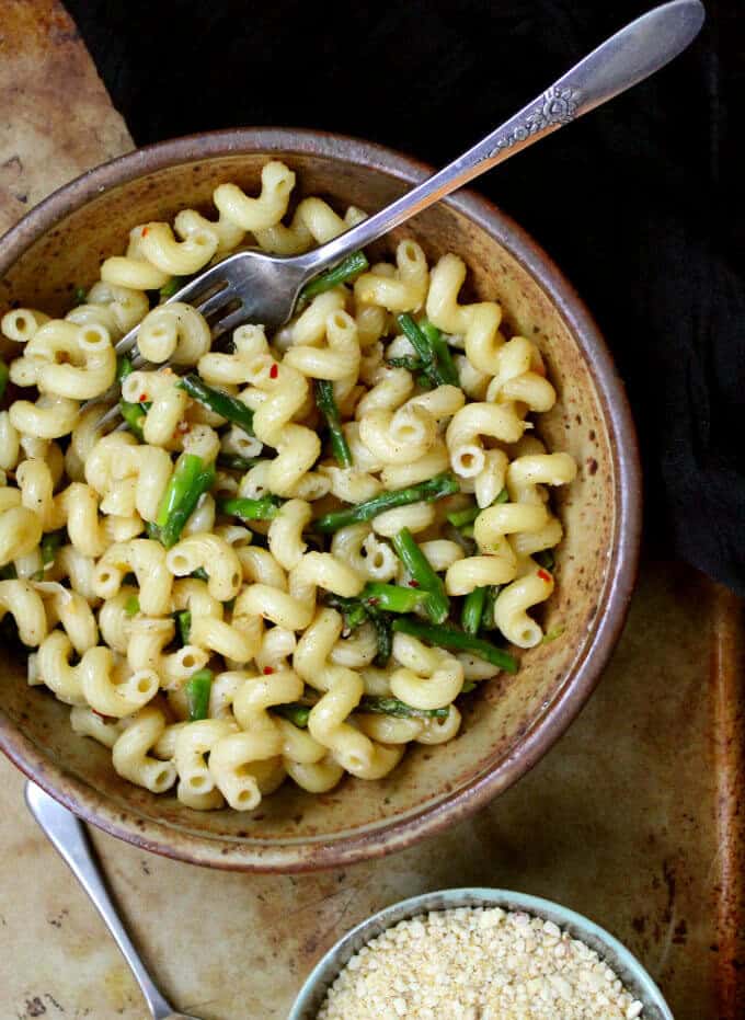 Garlicky Pasta with Asparagus in large pasta bowl with vegan parmesan on the side.