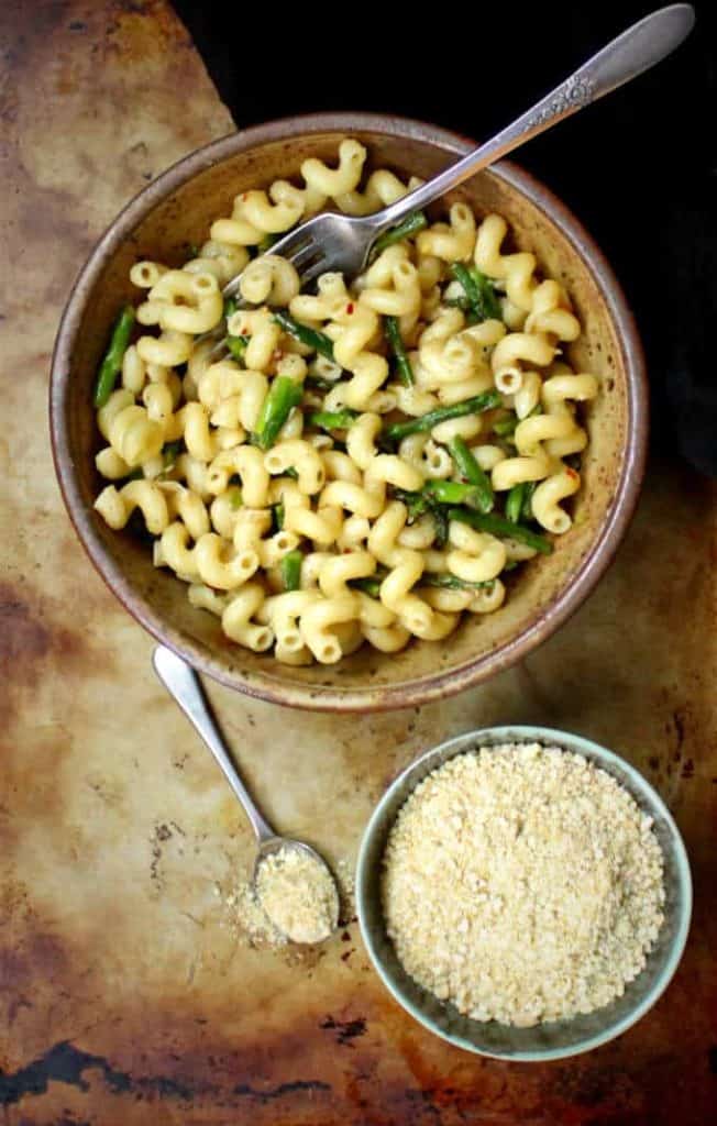 Garlicky Pasta with Asparagus in bowl with a bowl of vegan parmesan on the side.