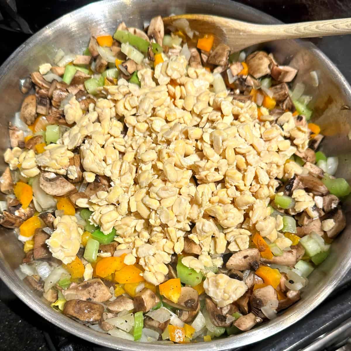 Crumbled tempeh added to veggies in skillet.