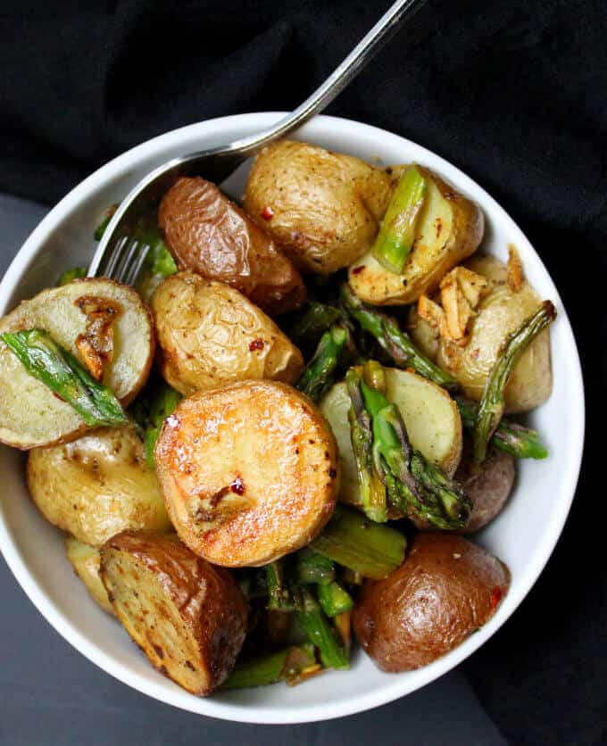Overhead shot of a bowl of Garlicky Roasted Asparagus and Potatoes with a fork.