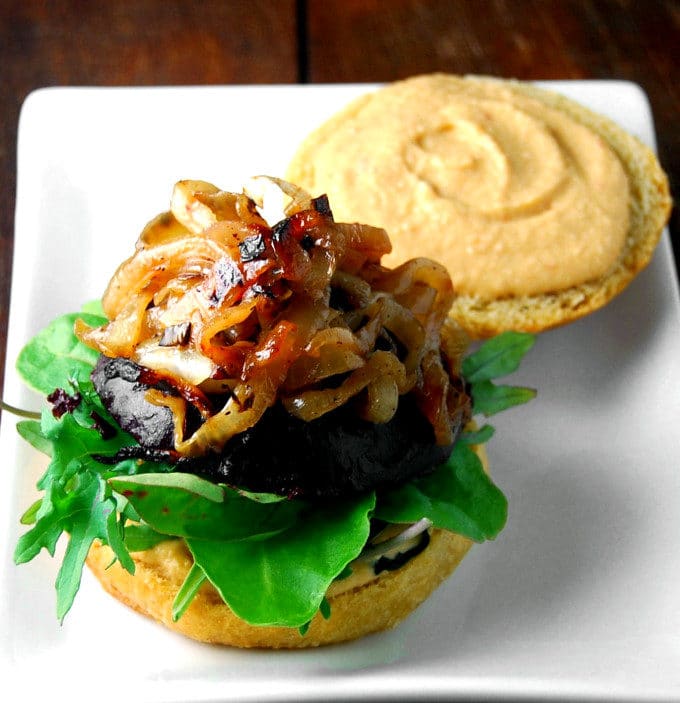 Photo of an open-faced Vegan Beet Burger with chipotle hummus, beet burger patty and caramelized onions.