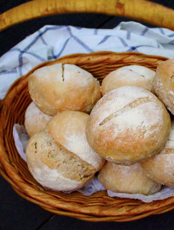 Crusty Sourdough Dinner Rolls in a wicker basket with a white and blue cloth napkin
