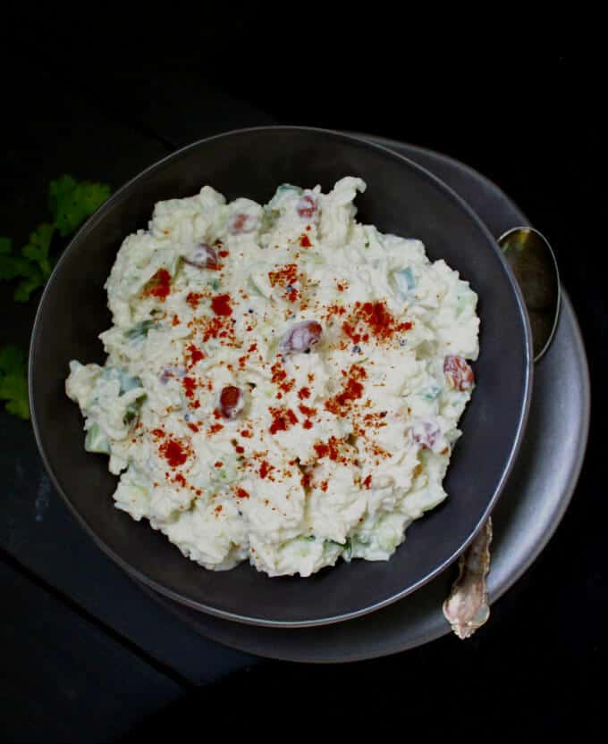 Vegan Cucumber Yogurt Rice or Curd Rice in black bowl with paprika scattered over.
