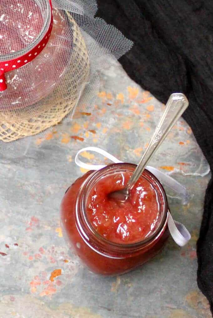 Glass jars filled with homemade vegan rhubarb jam with a spoon.