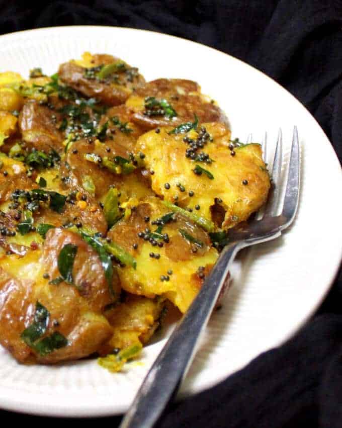 Smashed Potato Salad with Turmeric and Curry Leaves Dressing in white plate with fork.