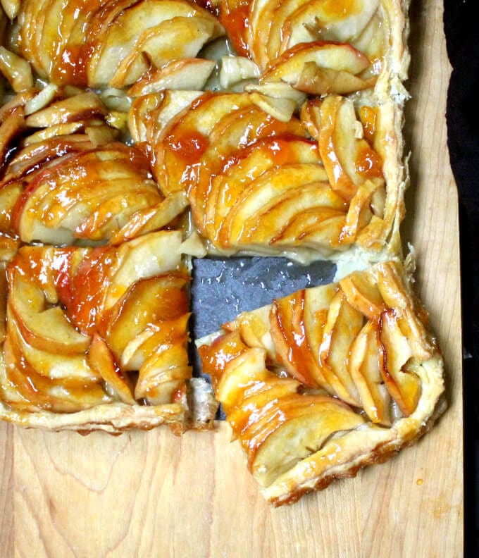 An elegant and easy French Apple Tart that looks deceptively complex, but comes together in less than 20 minutes. Sliced apples are arranged on a golden puff pastry base and all of this deliciousness is amped up by an apricot glaze. A vegan, soy-free and nut-free recipe.. #vegan #Thanksgiving #soyfree #nutfree #apple #pie HolyCowVegan.net