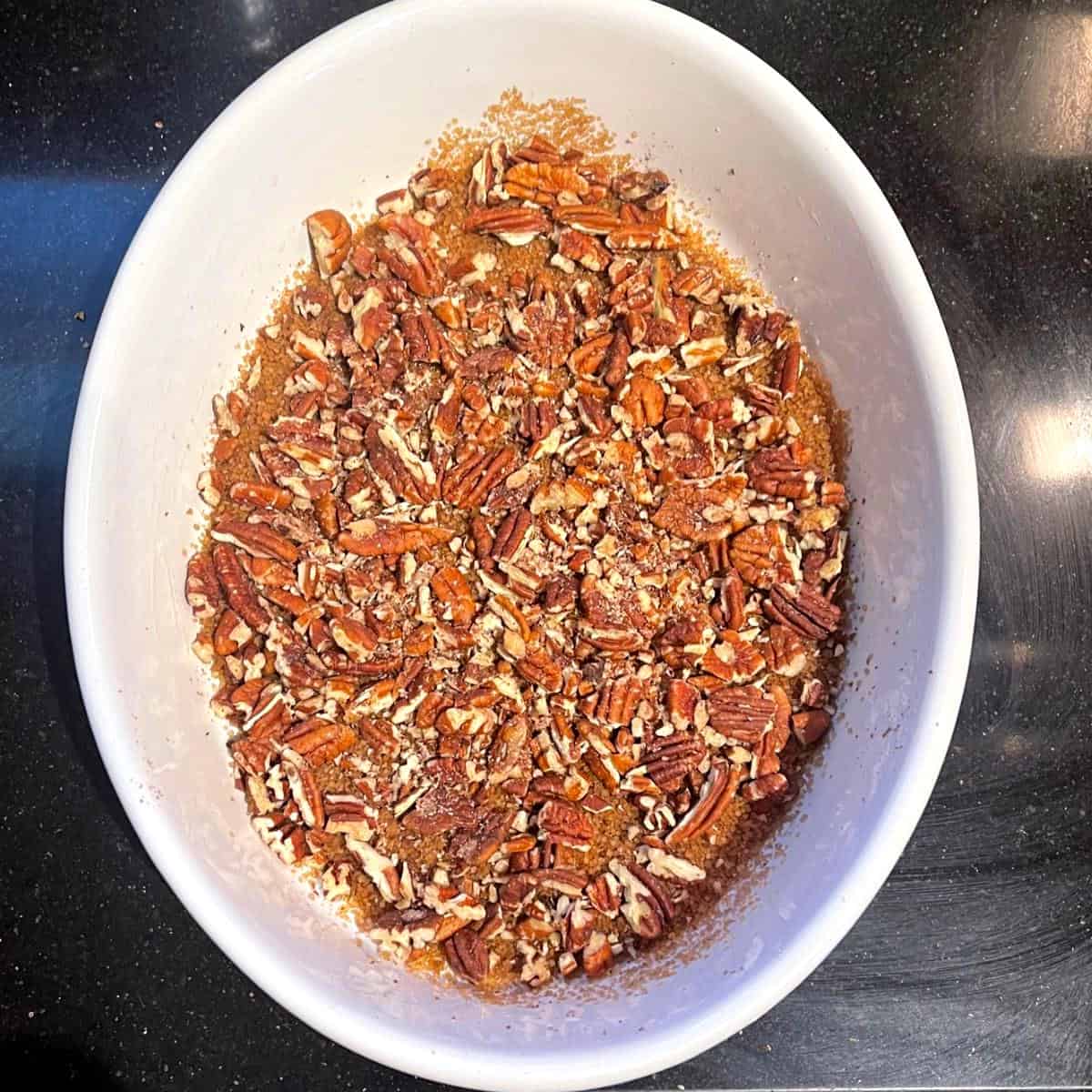 Sugar and pecans in oval baking dish.