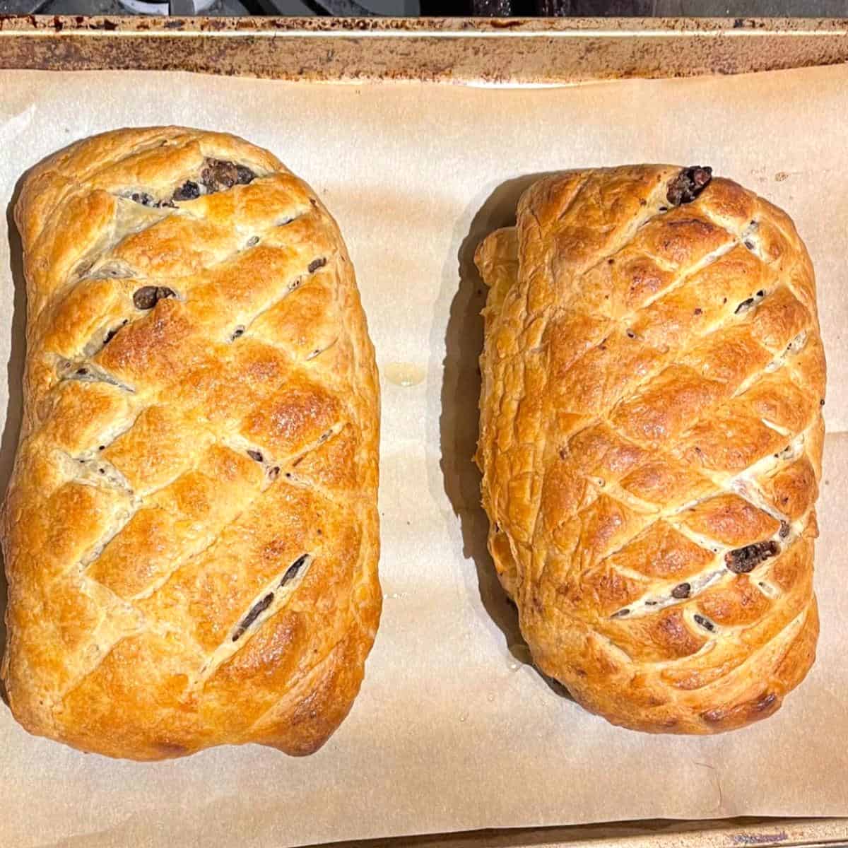 Baked wellington loaves on parchment lined baking sheet.