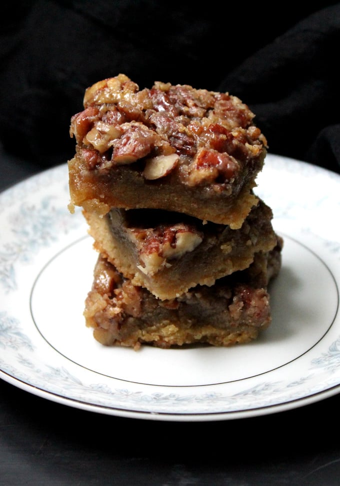 Stack of vegan pecan pie bars on a blue and white china plate.
