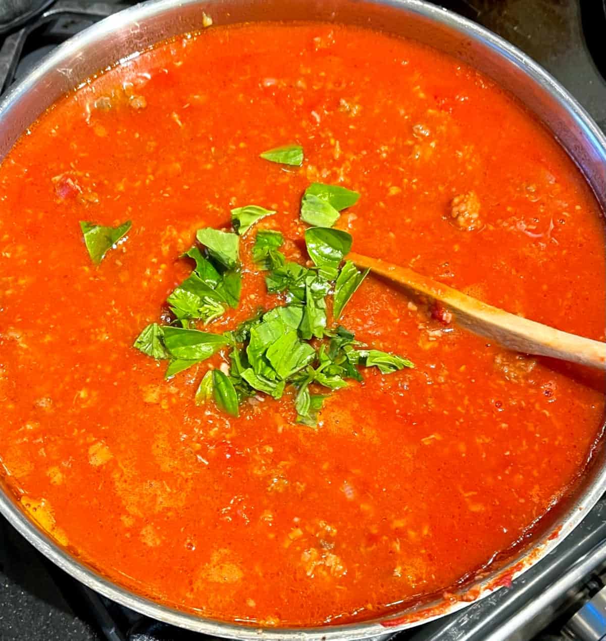 Basil and oregano added to tomato sauce.