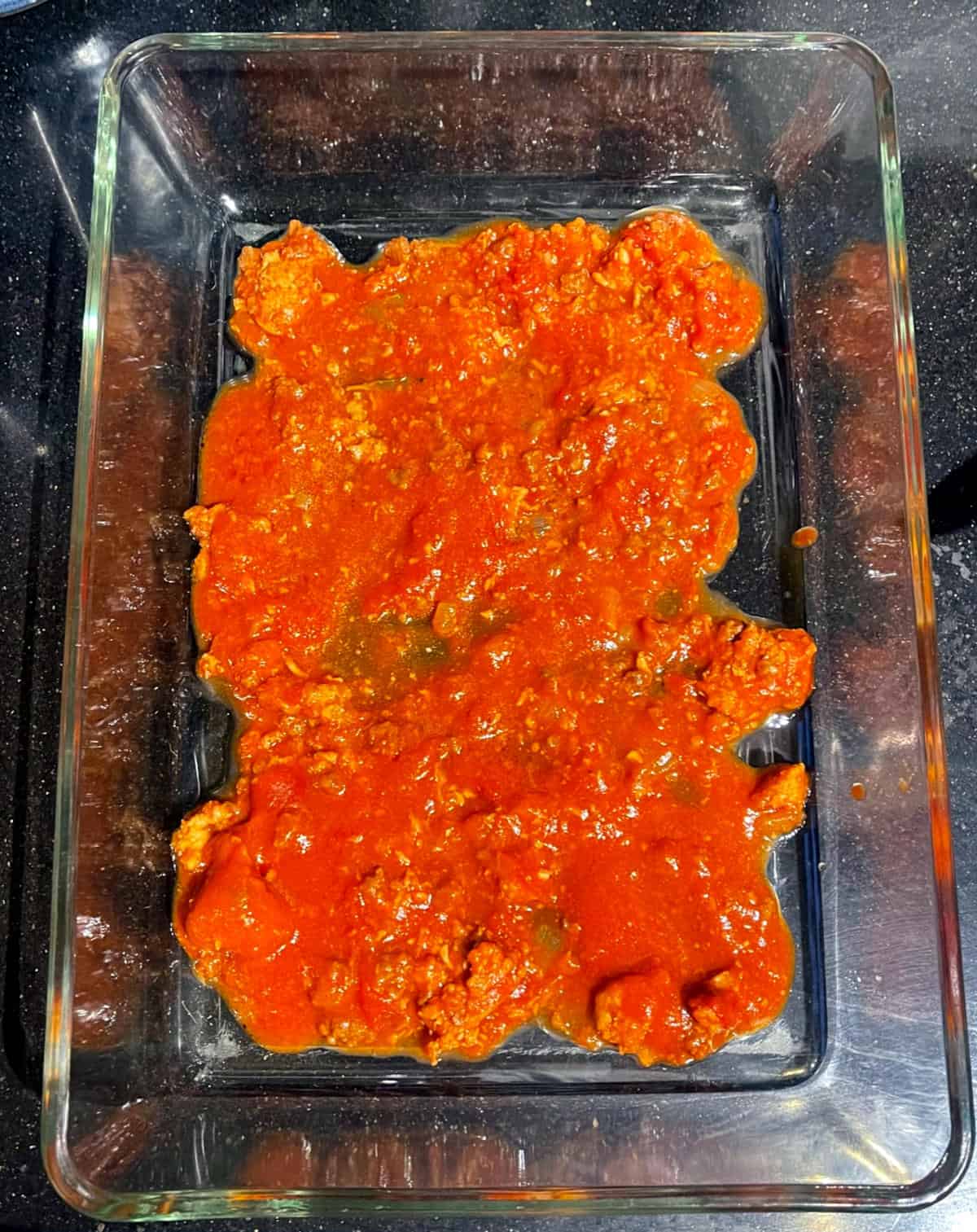 Tomato marinara layered in lasagna baking pan.