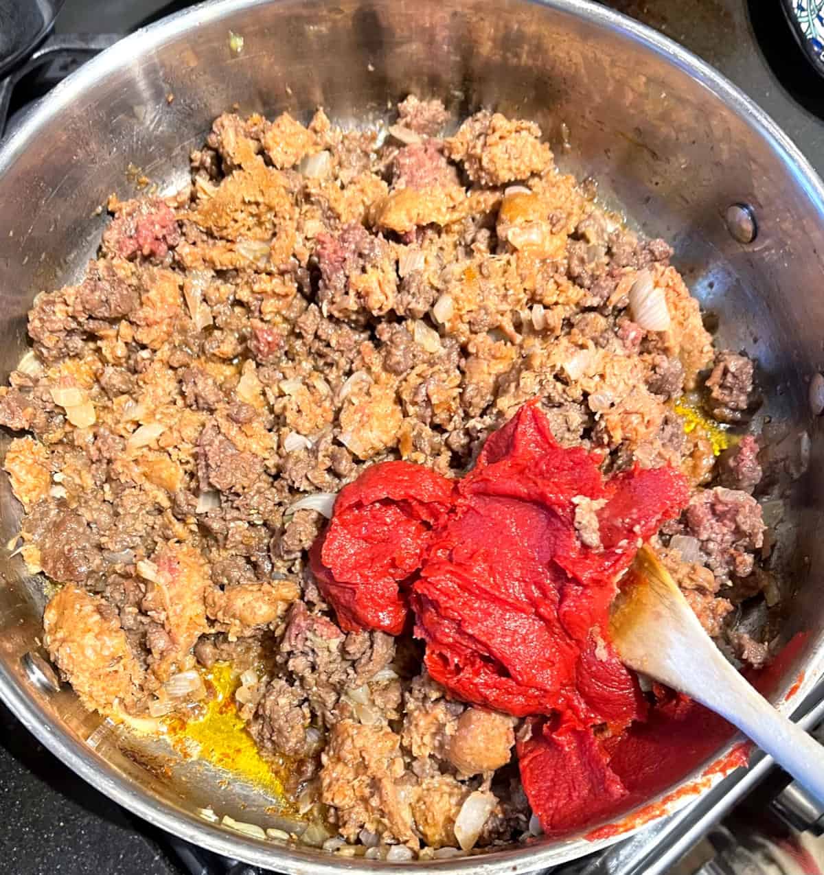 Tomato paste added to vegan meats in saute pan.