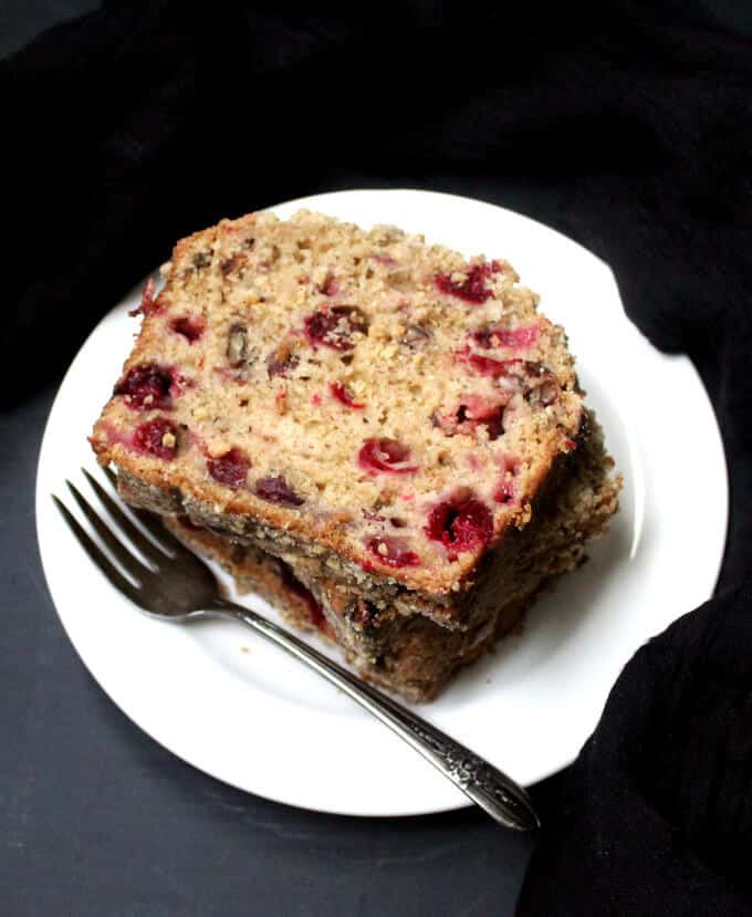 Cranberry Breakfast Bread slices stacked in white plate with fork.