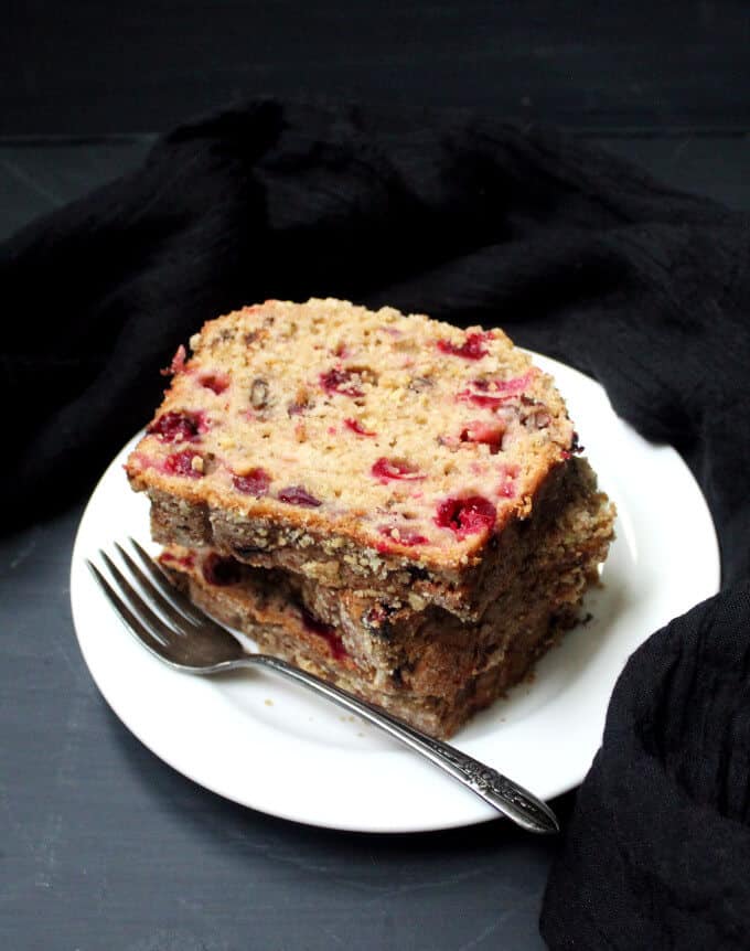 A stack of vegan cranberry breakfast bread slices in white plate with fork.