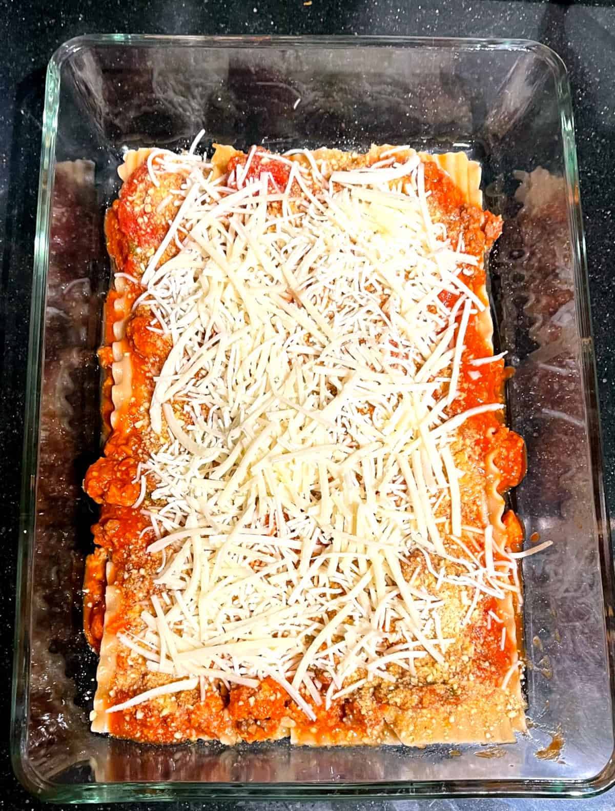 Vegan mozzarella layered over tomato sauce.