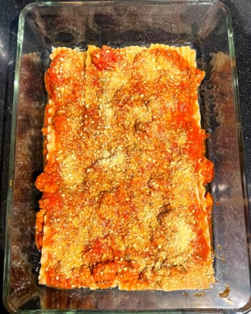 Vegan parmesan layered over tomato marinara.
