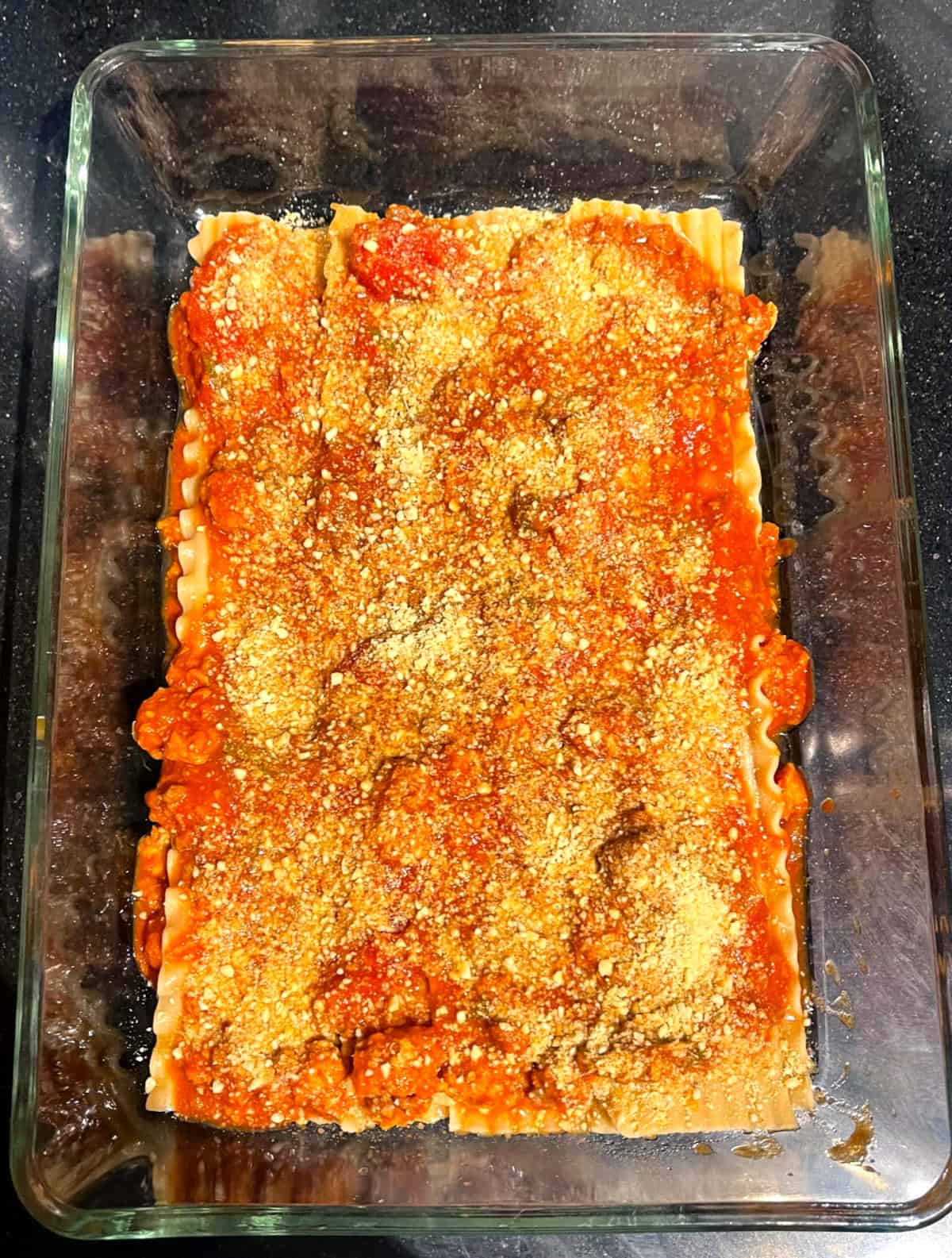 Vegan parmesan layered over tomato marinara.