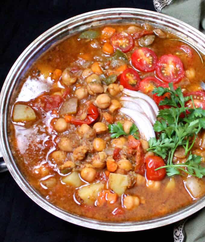Chickpea stew in a silver server on a black table