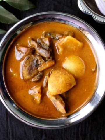 A steel and copper bowl with mushroom curry with potatoes
