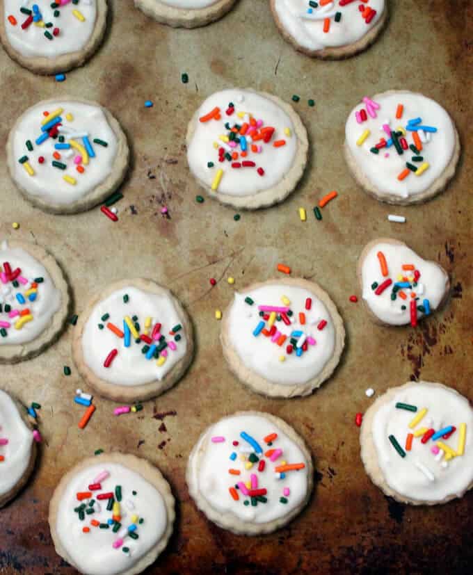 Glutenfree sugar cookies with sprinkles and icing on cookie sheet.