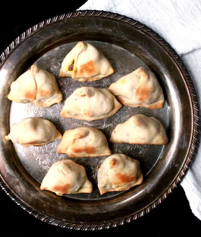 Photo of baked samosas in a round silver platter.