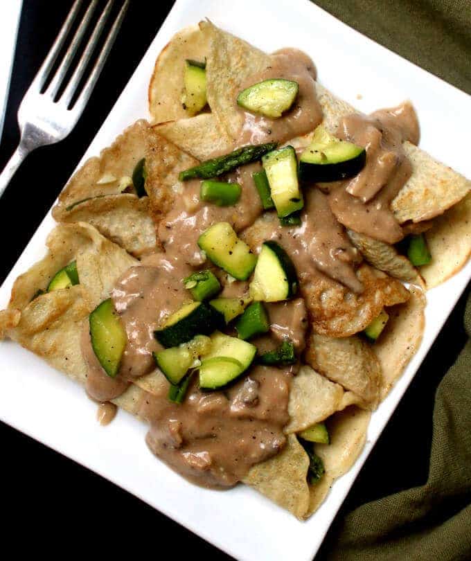 Savory Vegan Crepes with Mushroom Sauce and a light filling of veggies on a white rectangular plate.