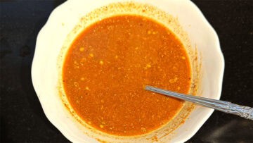 Tomato paste mixed with spices and water in bowl.